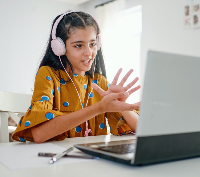Chica en un escritorio utilizando una computadora portátil e iniciando Norton Family.